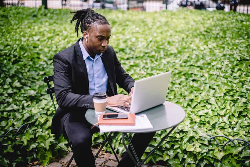 person focused on laptop sitting outside