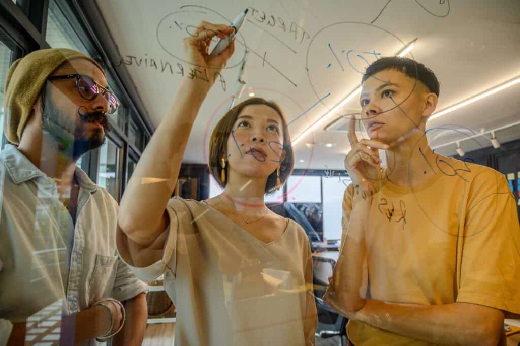 Coworkers writing on a glass wall