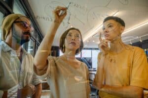 Coworkers writing on a glass wall