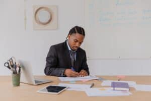 man at desk writing in notebook