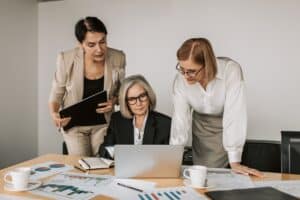 three women hovered over computer