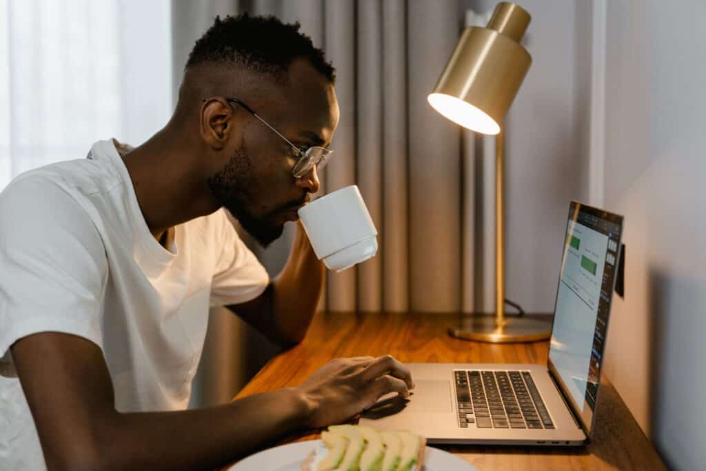 person drinking from a mug while looking at computer