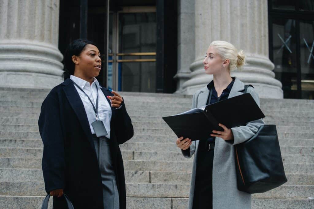 two women working in corporate law talking outside of court