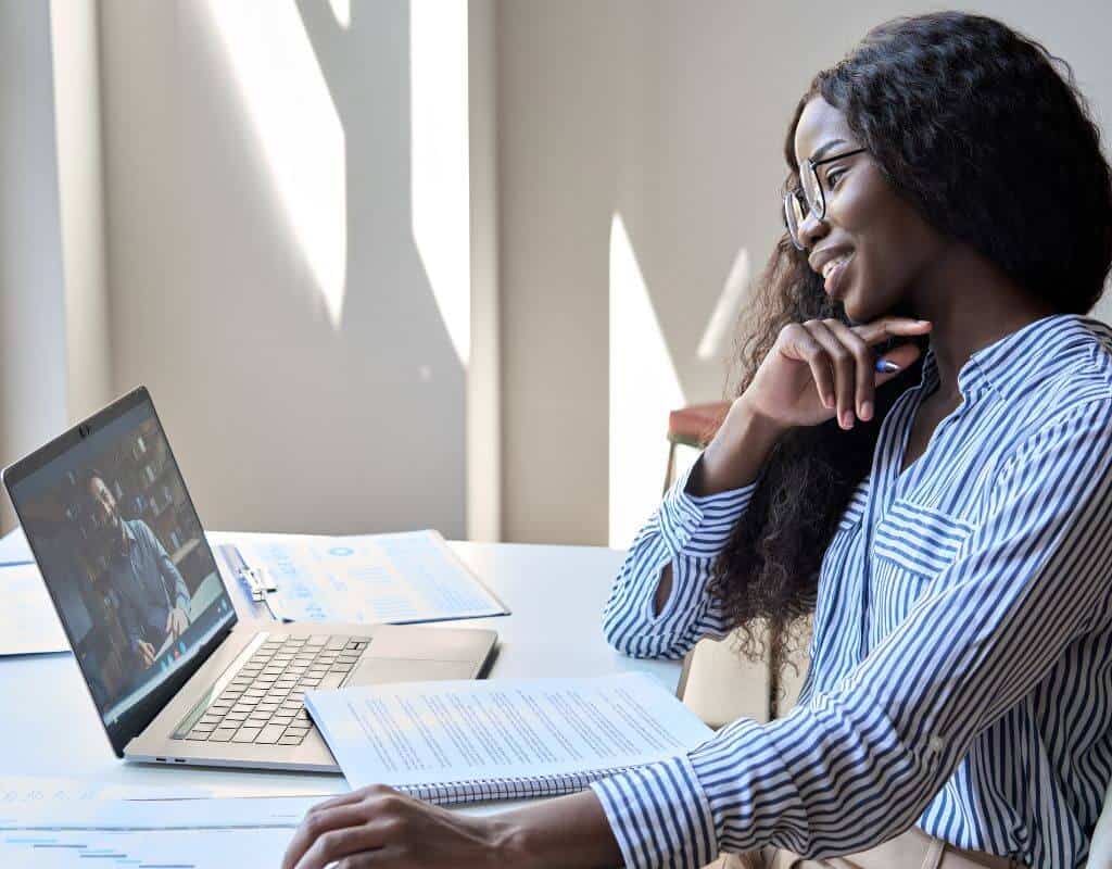 woman sitting at desk with laptop open to virtual meeting