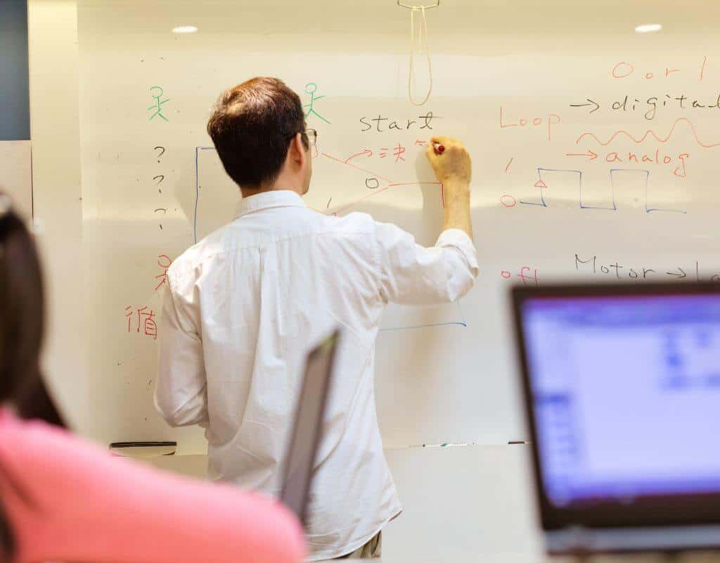 A man answering technical interview questions at a whiteboard