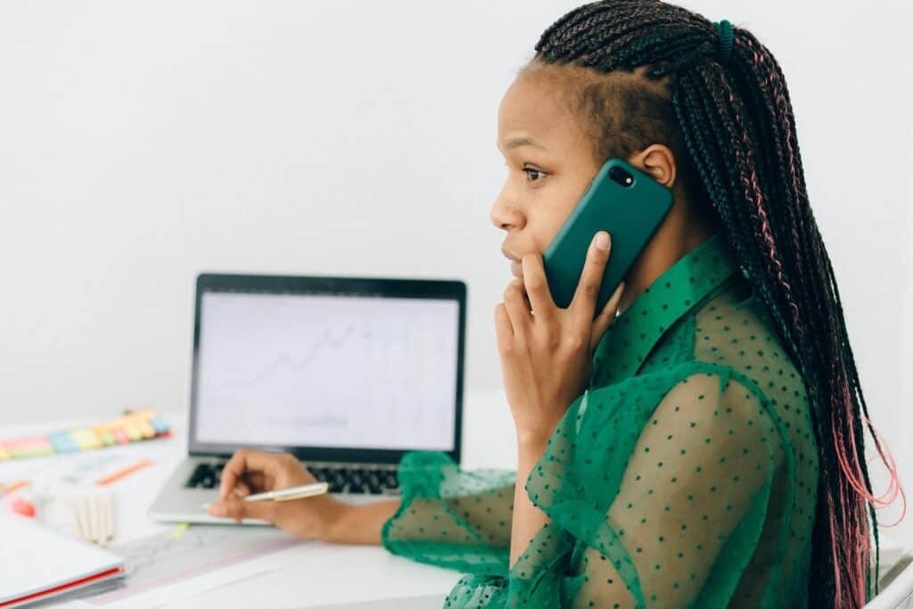 woman talking on the phone with laptop in front of her