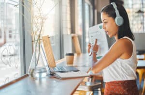 A woman giving a presentation on a video call while working remotely from a coffee shop