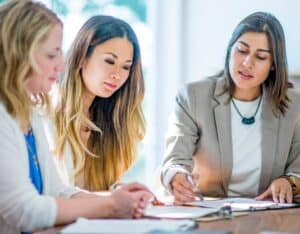 Three businesswomen in finance comparing NPVs (net present values)