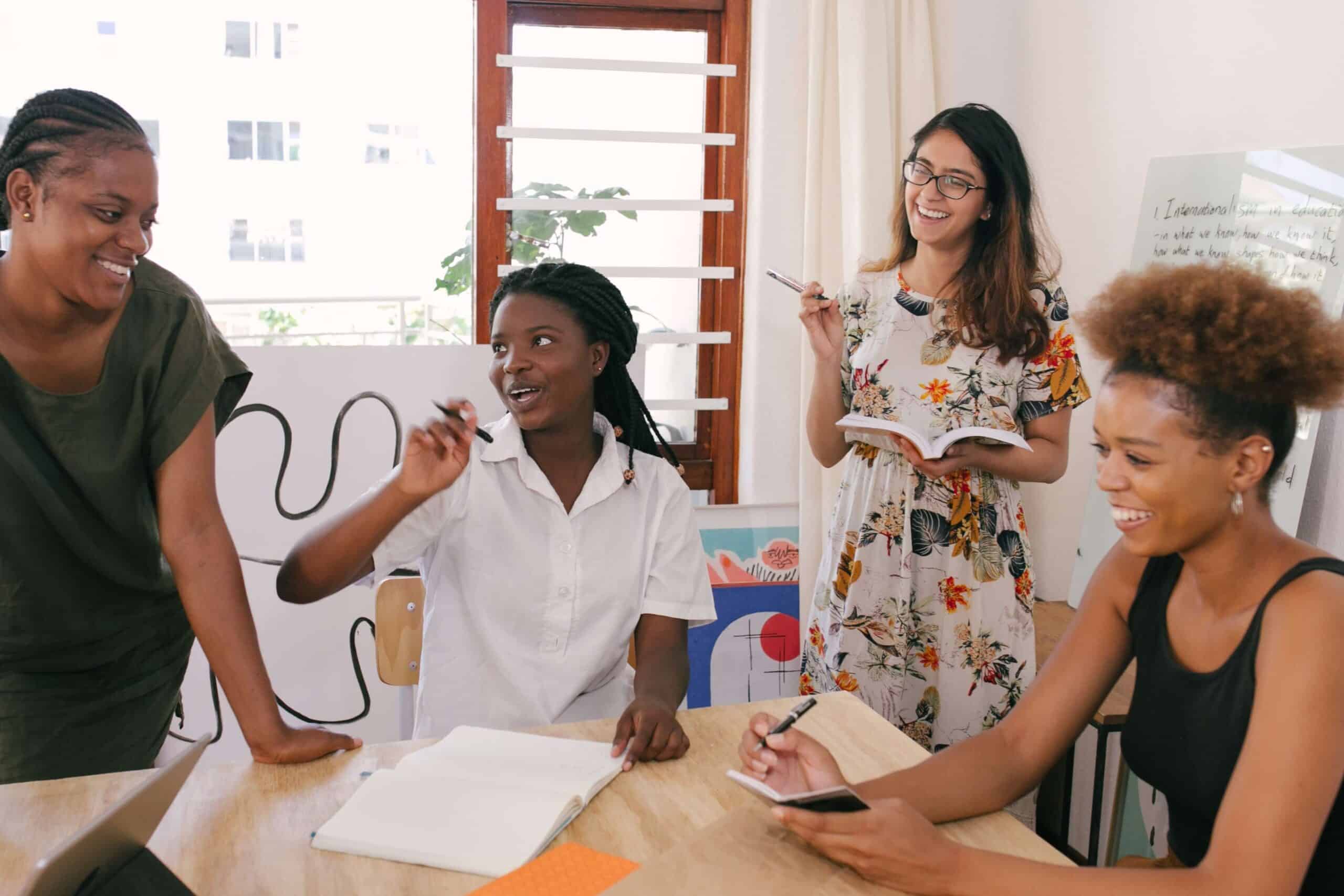 group of employees at work surrounding a desk and smiling