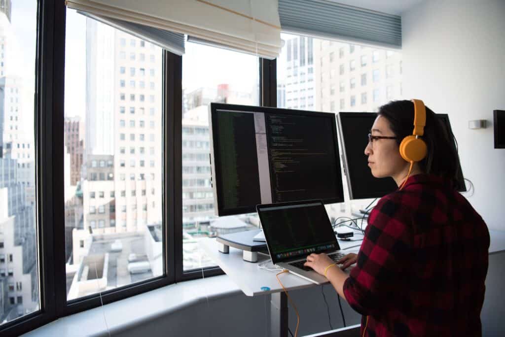full-stack engineer sitting in front of three computer screens with code