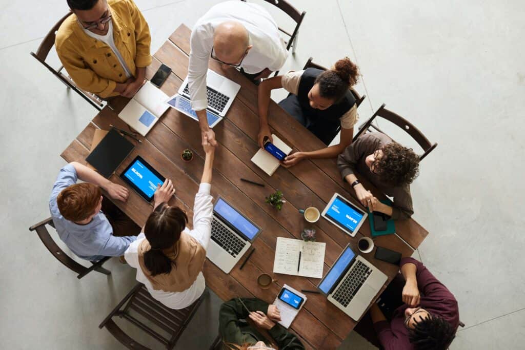 coworkers sitting around a table with laptops open