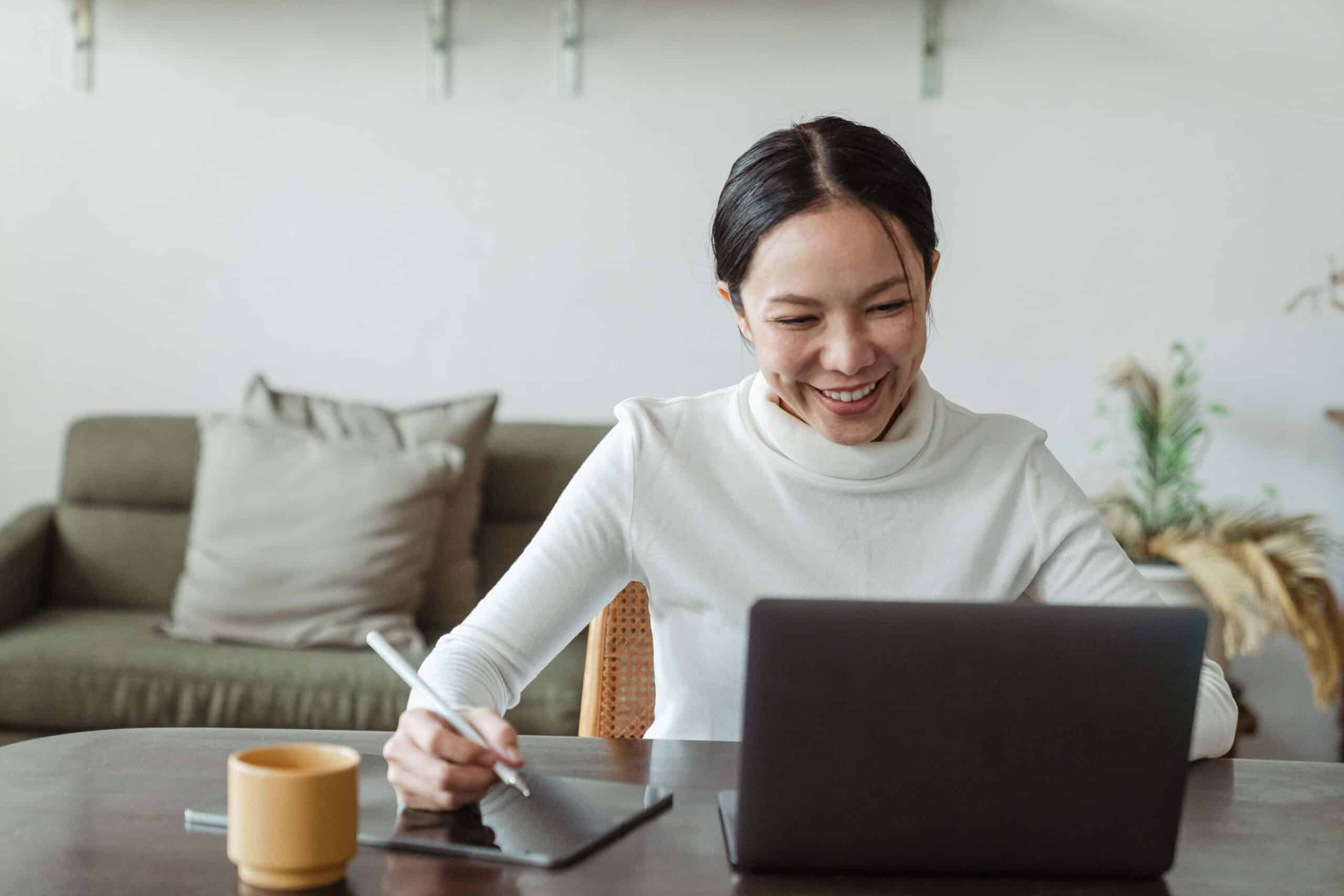 woman looking at computer and taking notes