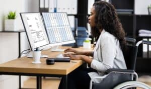 woman in a wheelchair at a desk doing work