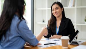 A job interview candidate and hiring manager shake hands after going through job interview questions and answers